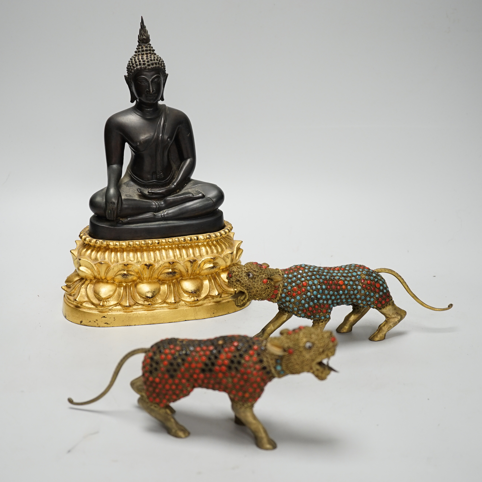 A Thai bronze Buddha raised on a gilt base and two filigree work brass and enamel tigers , the largest 26cm high